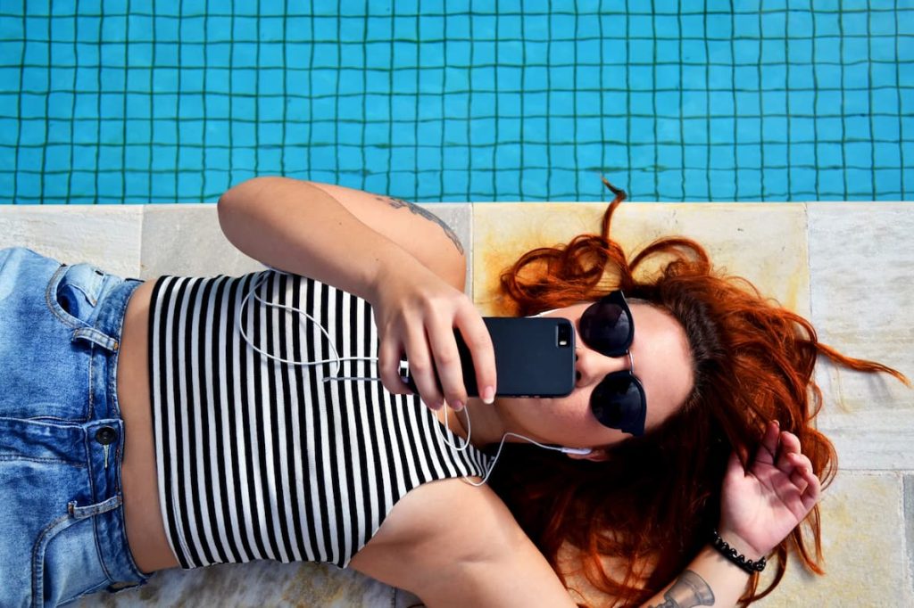 Menina a beira de piscina acompanha no site alfinetei as fofocas dos famosos.