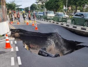 Carro cai em cratera gigante no meio da rua e deixa mulher ferida; veja VÍDEO