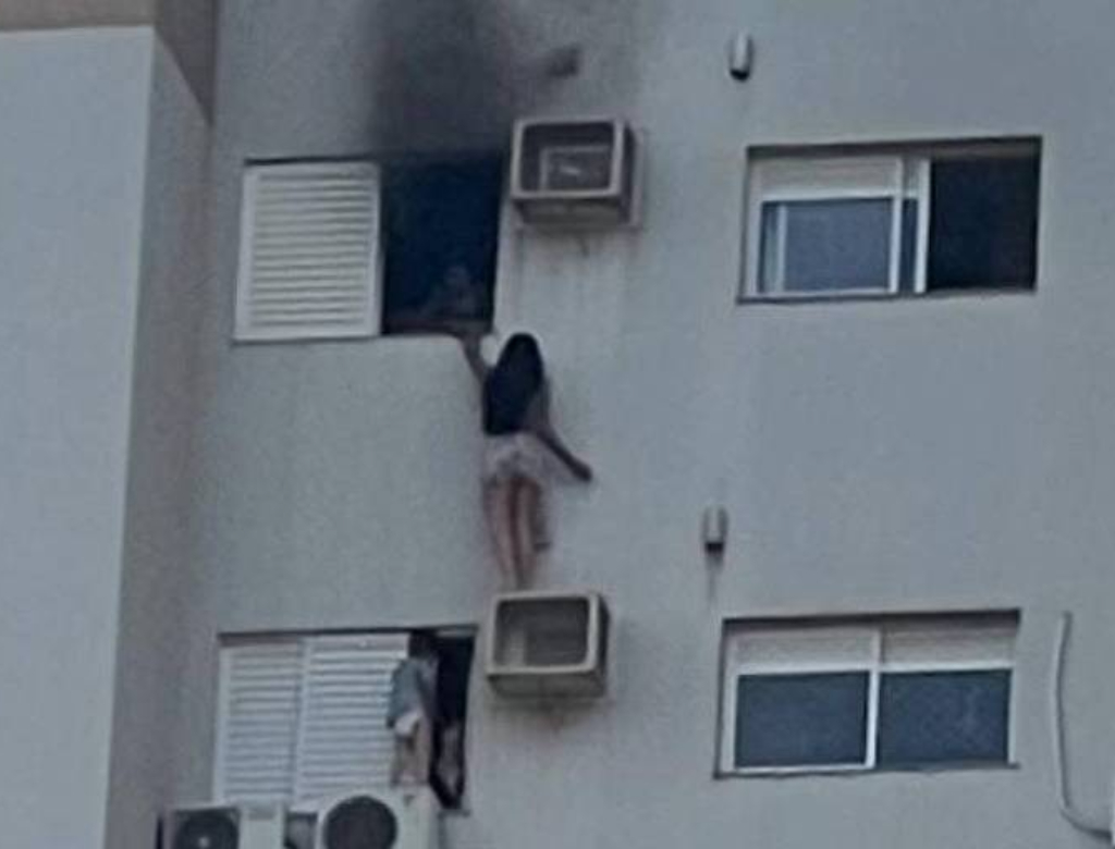 Mulher pendurada em ar-condicionado (Foto: Reprodução)
